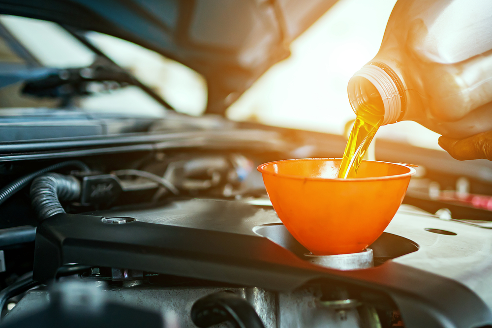 A Chevrolet service technician pouring new oil into a car's engine