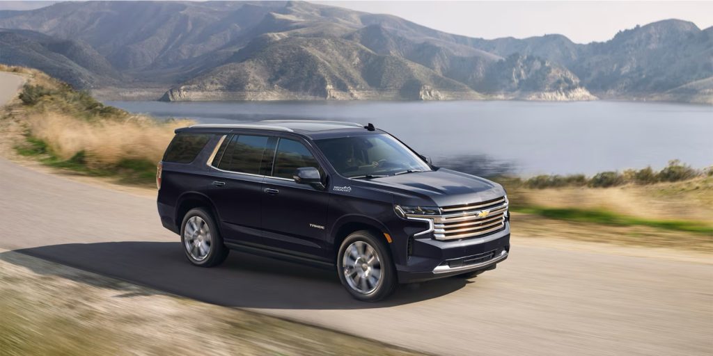 A 2024 Chevrolet Tahoe driving in the outdoors by a lake.