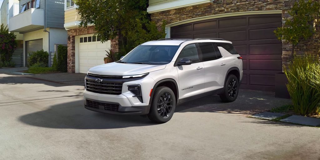 A white 2024 Chevrolet Traverse SUV parked in front of a house.