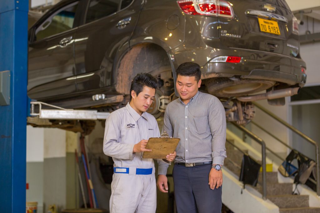 A Chevrolet mechanic speaking to a customer about the service check of a Chevrolet vehicle.
